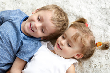 Cute funny children lying on carpet at home