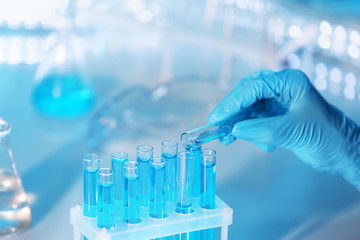 Hand in glove pouring a sample into a  test tube, closeup
