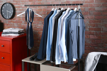 Casual stylish male clothes on hanger stand in room
