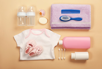 Baby clothes and necessities on color background