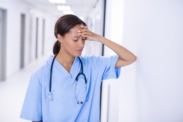 Tensed female doctor standing in corridor