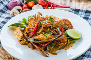 spicy stir fried spaghetti with seafood and basil leaves on whit