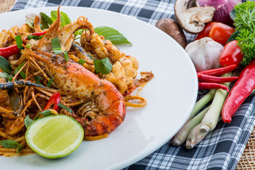 spicy stir fried spaghetti with seafood and basil leaves on whit