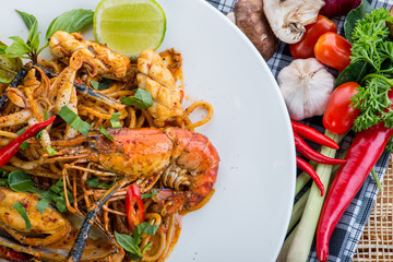spicy stir fried spaghetti with seafood and basil leaves on whit