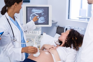 Doctor doing ultrasound scan for pregnant woman - Powered by Adobe