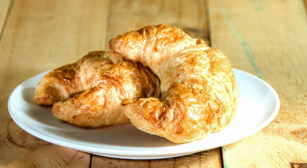 Croissant in plate on wooden tabletop