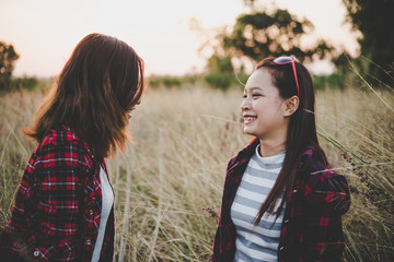 Close up of two girls. Close friends in field with sunset.