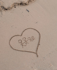 Heart drawn in sea beach sand, family concept