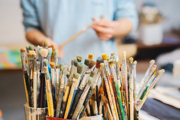 Paint Brushes on a blur background and artist is holding the brush