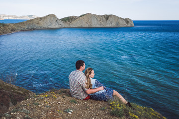 Fototapeta na wymiar Couple relaxing by the sea with amazing mountain view. Jeans jacket