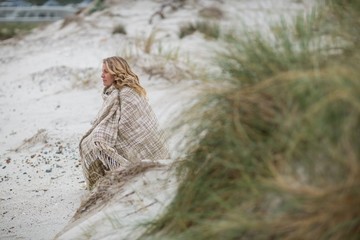 Mature woman wrapped in shawl on the beach