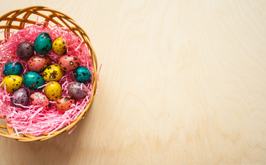 Easter. Colorful eggs in a basket  on wooden background