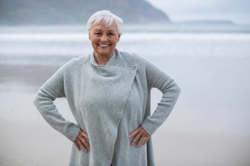 Smiling senior woman standing with hands on hip - Powered by Adobe