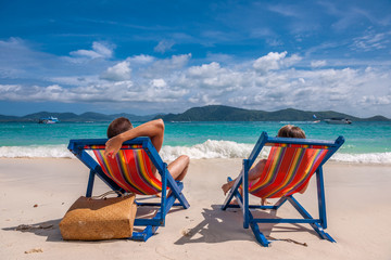 Fototapeta na wymiar Couple on tropical beach in loungers