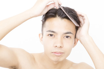 Naklejka premium メンズビューティ 整髪 ヘアースタイルを整える 寝ぐせ直し アップ カメラ目線 白バック