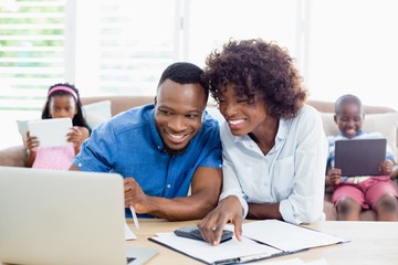 Couple sitting at table and calculating bills