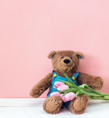 Teddy bear with a bouquet of pink tulips.
