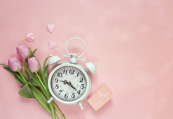 Background with white alarm clock, gift box, tulips and hearts o