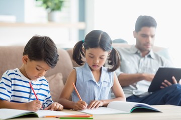 Attentive siblings doing homework in living room