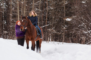 Teenager girl, mom and horse in a winter