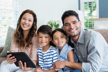 Parents and kids using digital tablet in living room at home