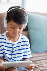 Naklejka premium Boy listening music on digital tablet in living room
