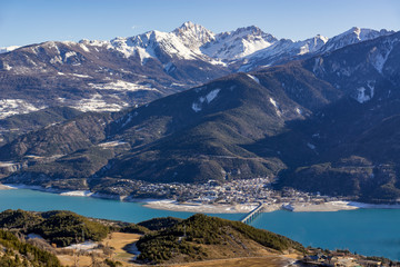 Elevated view over Savines-le-Lac Village and Serre Poncon lake in winter. In the distance the Montagnette and Pouzenc mountain peaks. Hautes-Alpes, Southern Alps, France