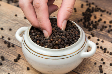 Black pepper grain in the bowl on the table in the kitchen. Healthy eating and lifestyle.