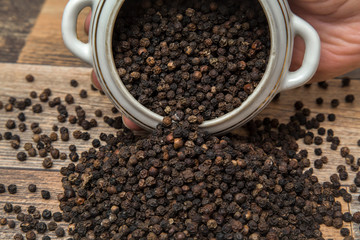 Black pepper grain in the bowl on the table in the kitchen. Healthy eating and lifestyle.