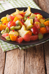Natural Food: Salad of fresh exotic tropical fruits close-up on a plate. vertical