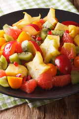 Salad of fresh tropical fruits close-up on a plate. vertical