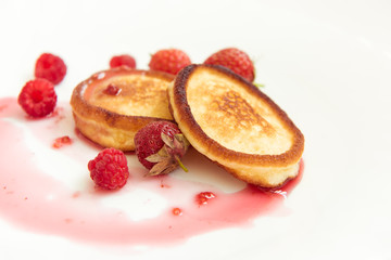 Pancakes, jam, strawberries, raspberries on a white plate