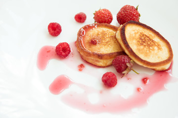 Pancakes, jam, strawberries, raspberries on a white plate