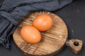 Eggs on a cutting board. On a dark table.