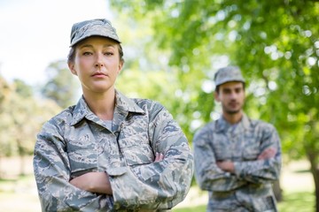 Portrait of a military couple standing with arms crossed in park