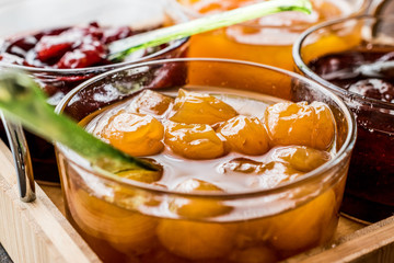 Yellow Plum jam in glass bowl  with spoon and various marmalades