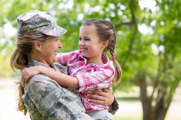 Happy female soldier with her daughter in park