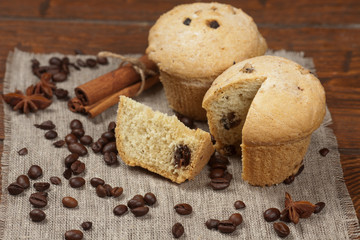 Tasty muffin cakes on burlap, spices and coffee beans
