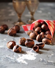 Roasted chestnuts in paper bags on a gray background. Healthy food.