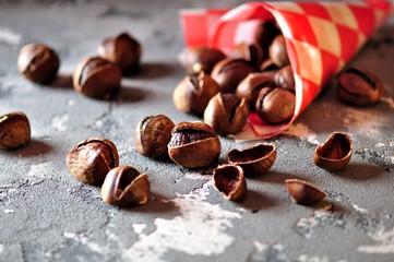 Roasted chestnuts in paper bags on a gray background. Healthy food.