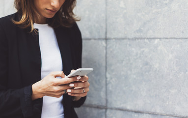 Portrait young businesswomen in black suit using smartphone isolated on background concrete gray wall mockup, pretty hipster manager holding mobile gadget, girl smiletexting message, connect