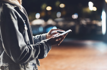 Girl pointing finger on screen smartphone on background illumination bokeh color light in night...