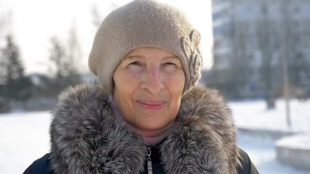 portrait aged smiling woman outdoors, winter time, slow motion