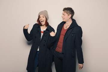 Happy young couple in winter clothes having fun in studio over white background