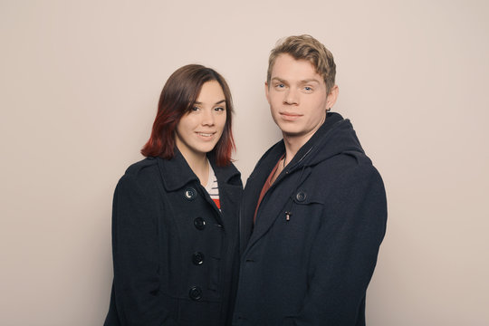 Happy young couple in winter clothes having fun in studio over white background