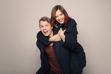Happy young couple in winter clothes having fun in studio over white background