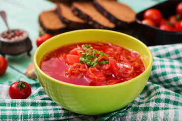 Traditional Ukrainian Russian vegetable borscht soup on green bowl.