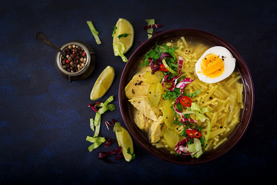 Noodle soup with chicken, celery and egg in a bowl on a black background. Flat lay. Top view.
