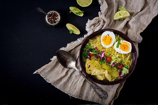 Noodle soup with chicken, celery and egg in a bowl on a black background. Flat lay. Top view.