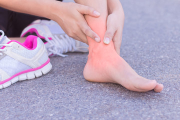 Young woman massaging her painful foot from exercising and runni